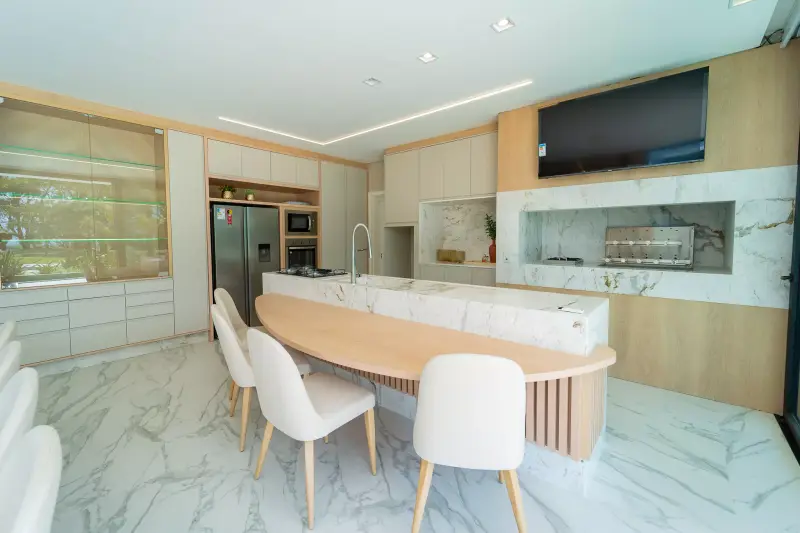 Cozinha gourmet com ilha em mármore, cristaleira e painel em madeira